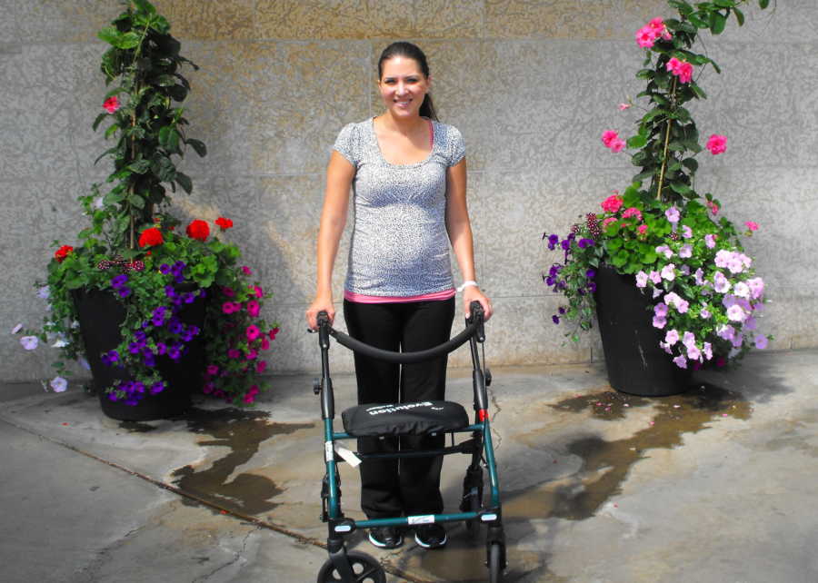 Woman with Guillain-Barre syndrome stands smiling outside on walker