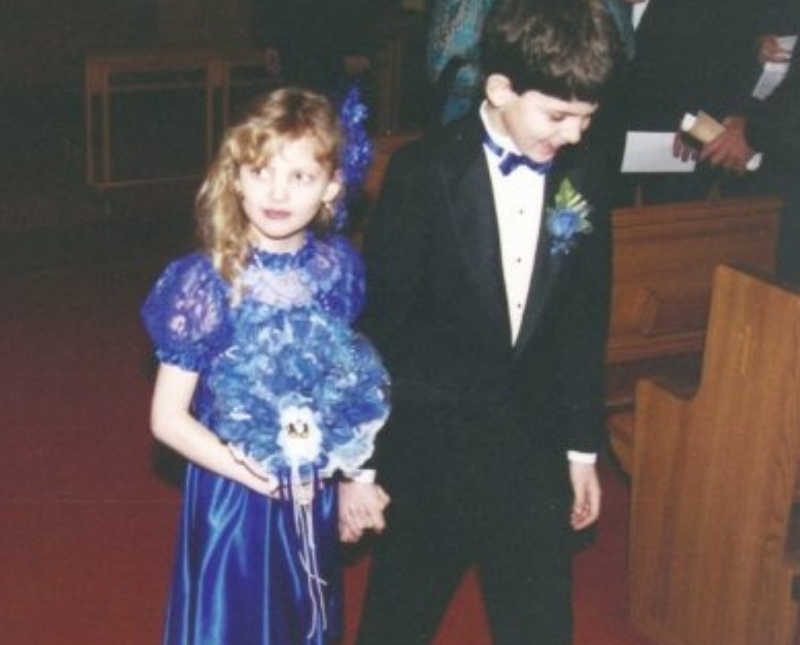 Young boy walks down aisle of church holding hands with little girl