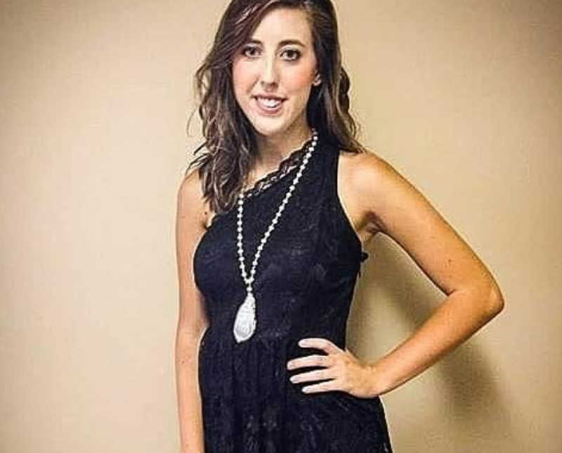Woman who escaped abusive relationship stands smiling with hand on hip