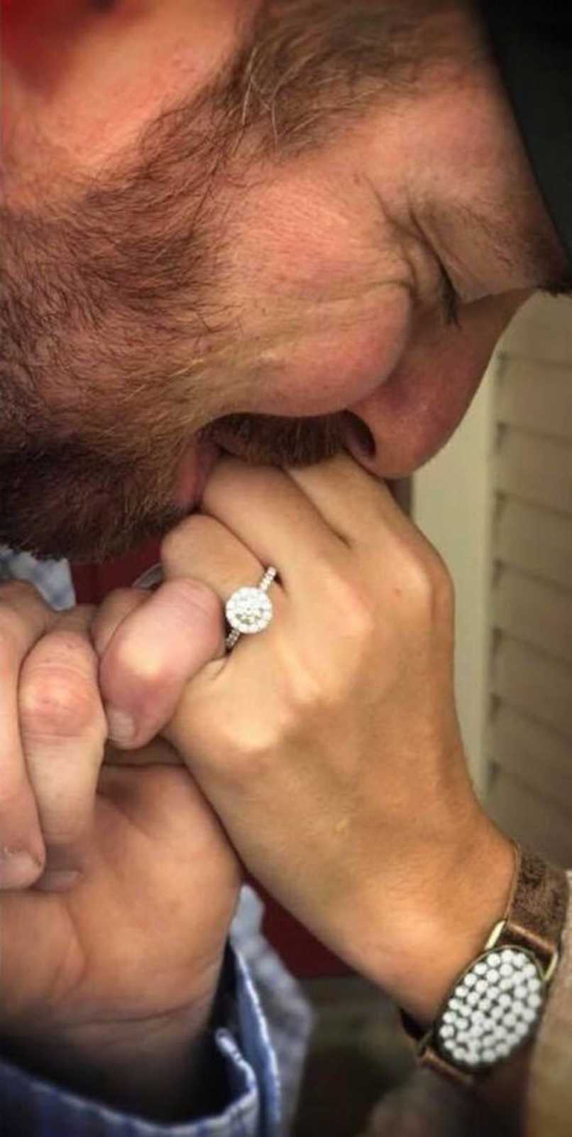 Man kisses fiancee's hand with ring on it