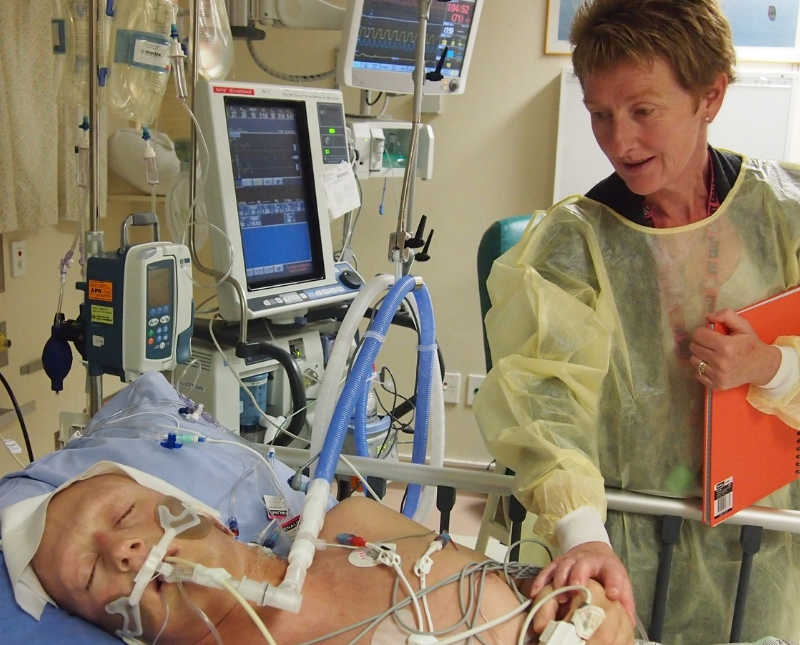 Intubated man who needs cell transplant lays in hospital bed at nurse stands over him