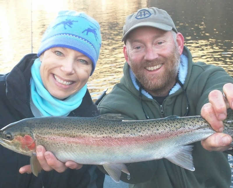 Husband and wife smile as husband holds fish he caught