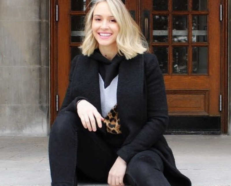 Woman who was abused sits on outdoor step of building smiling