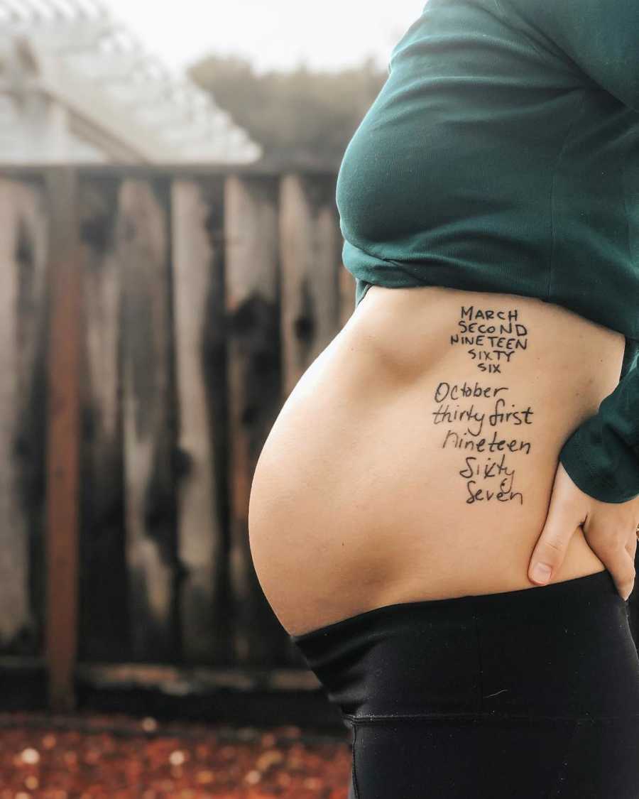 Pregnant woman stands outside with shirt raised to show tattoo on her said of deceased father's handwriting
