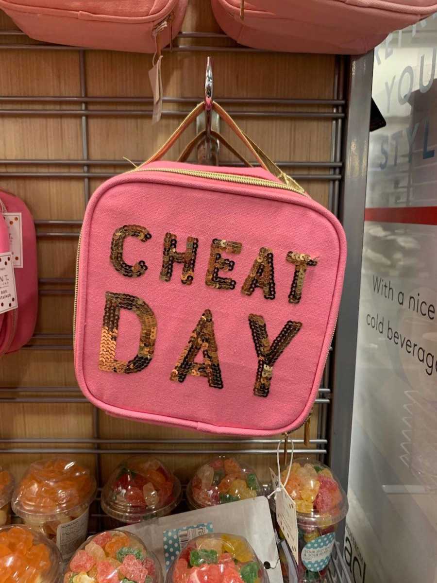 Lunchbox for sale at store that says, "cheat day" in gold sparkly letters