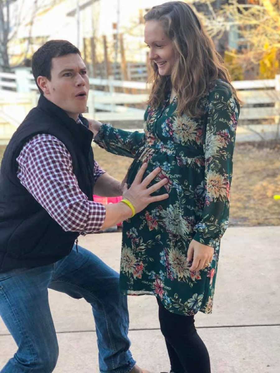 Husband who is complete opposite of wife stands outside holding pregnant wife's stomach