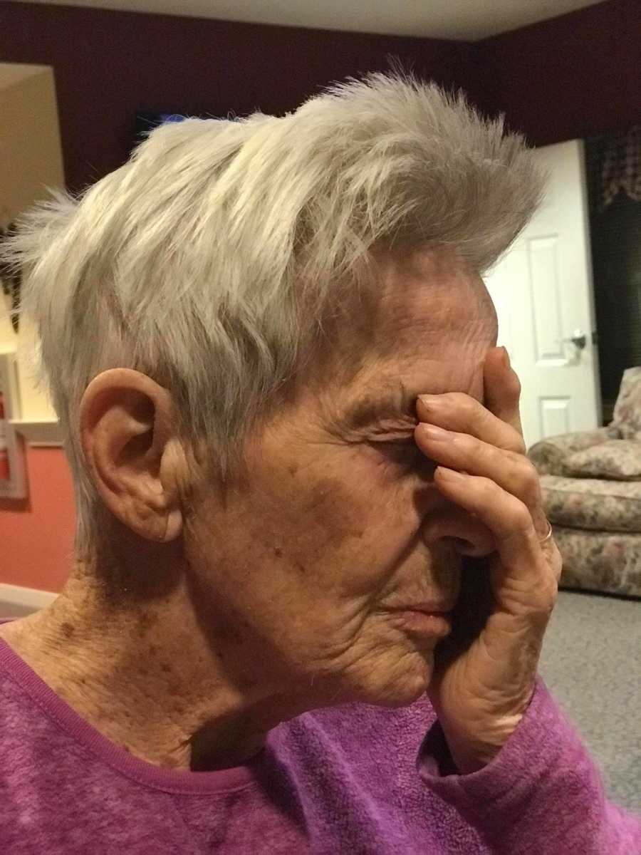 Elderly woman with dementia sits with hand over her face