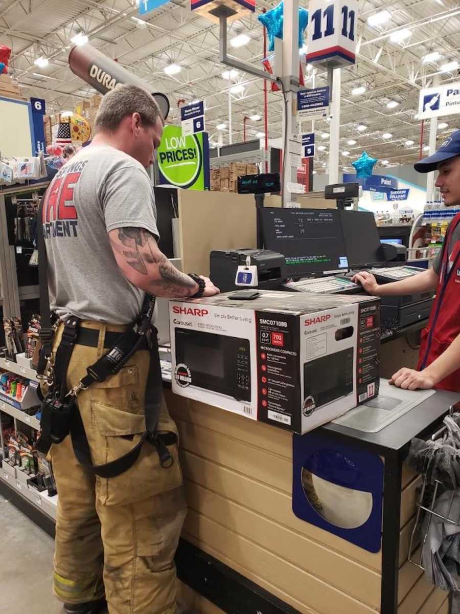 Fire fighter stands in check out lane of store buying a microwave