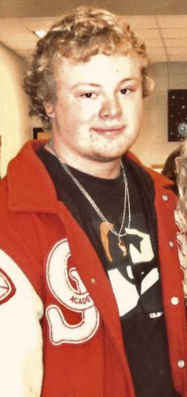 Teen stands smiling wearing varsity jacket