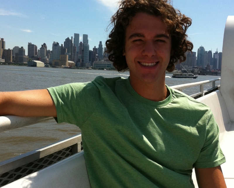 Man who has since passed from drug use stands smiling on ferry with city skyline in background