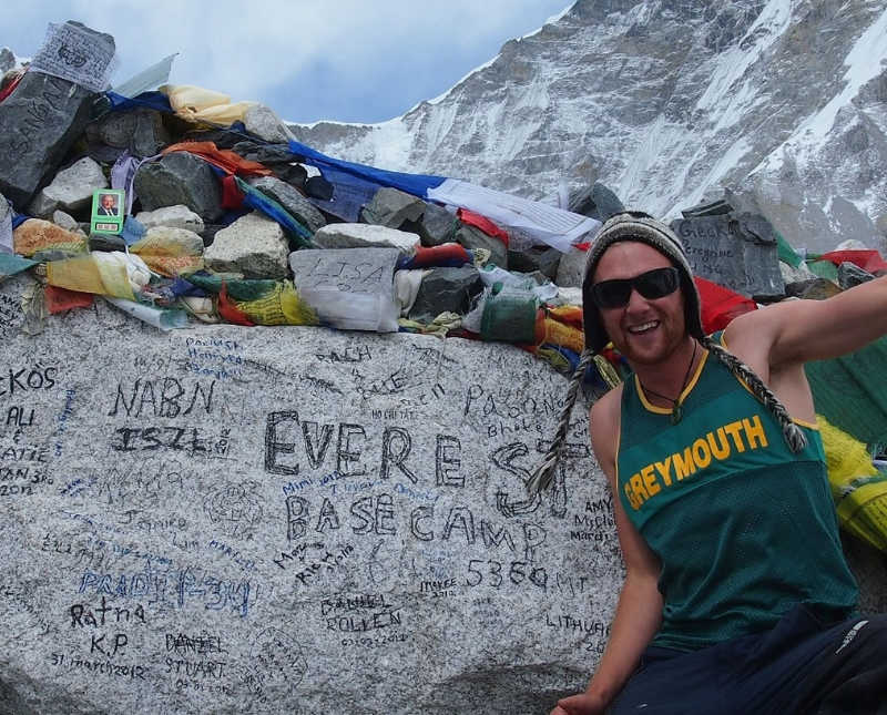 New Zealand track runner stands smiling in track jersey at base of Mount Everest
