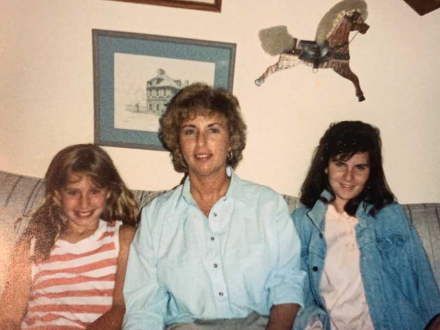 Mother sits on couch with her adopted daughter and biological daughter 