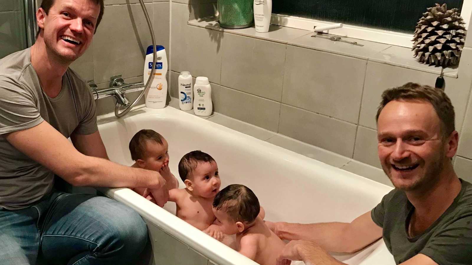 Fathers smile as they give their triplets a bath