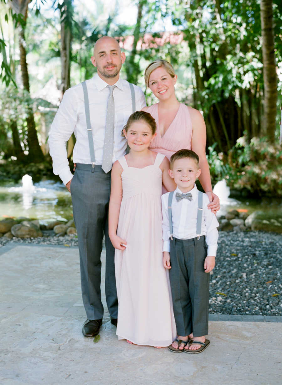 Husband who has since passed stands smiling beside wife and his two young kids who are in formal attire