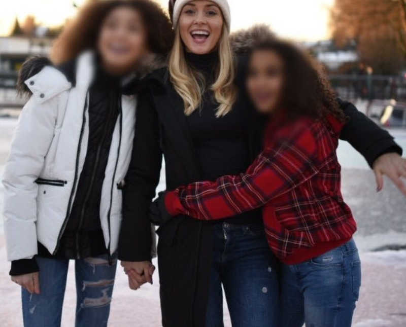 Woman who was domestically abused stands smiling with arms around her friends