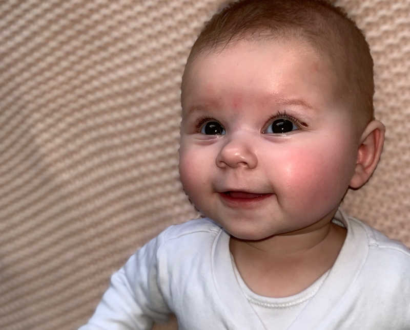 Baby girl with two mothers smiles while laying on her back