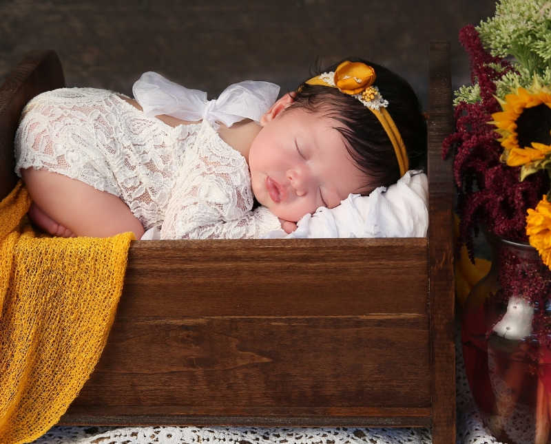 Newborn with Spina Bifida lays asleep in wooden drawer in photoshoot