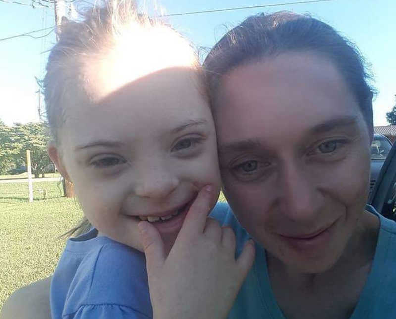 Mother smiles in selfie beside her daughter with down syndrome