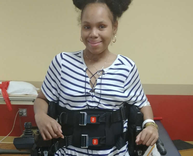 Young woman smiles as she sits in wheel chair in rehab