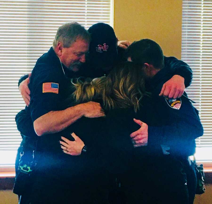 Dispatchers and EMT's stand in group hug