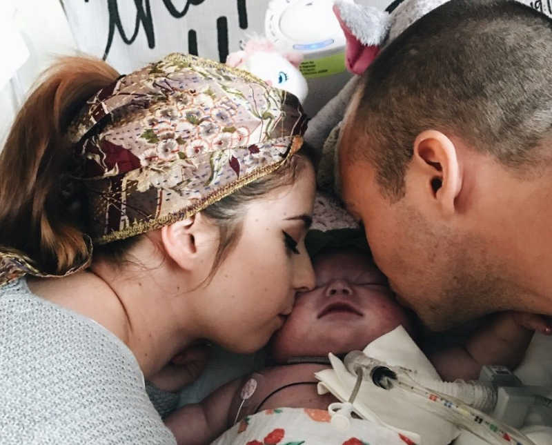 Mother and father kiss cheek of newborn with heart problems who would soon pass away