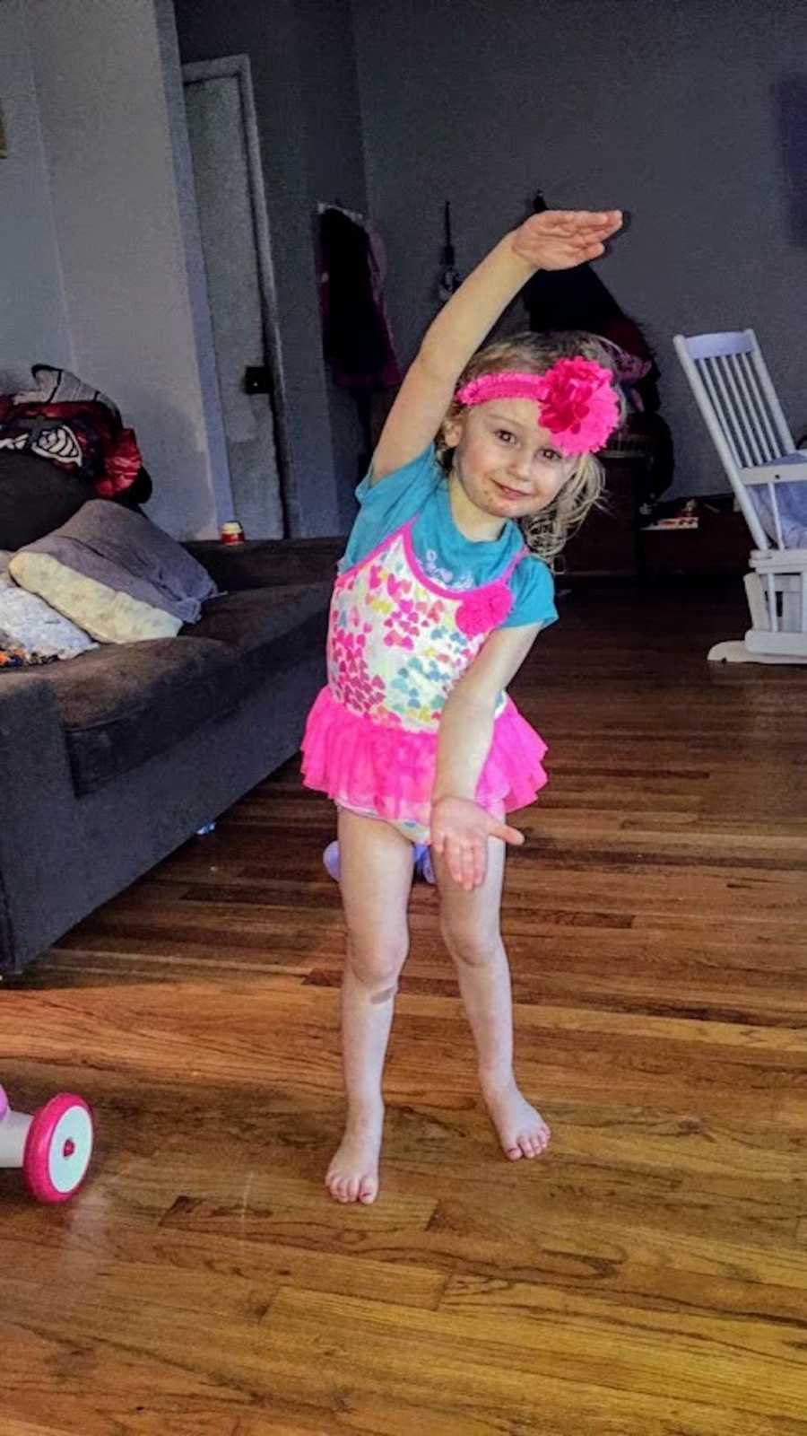 Little girl stands in home doing a ballet pose