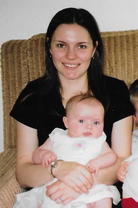 Woman smiles as she sits on couch with baby girl in her lap