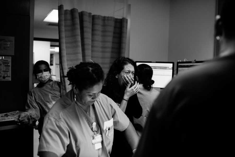 Woman cries in hospital room as she watches the birth of her adopted child