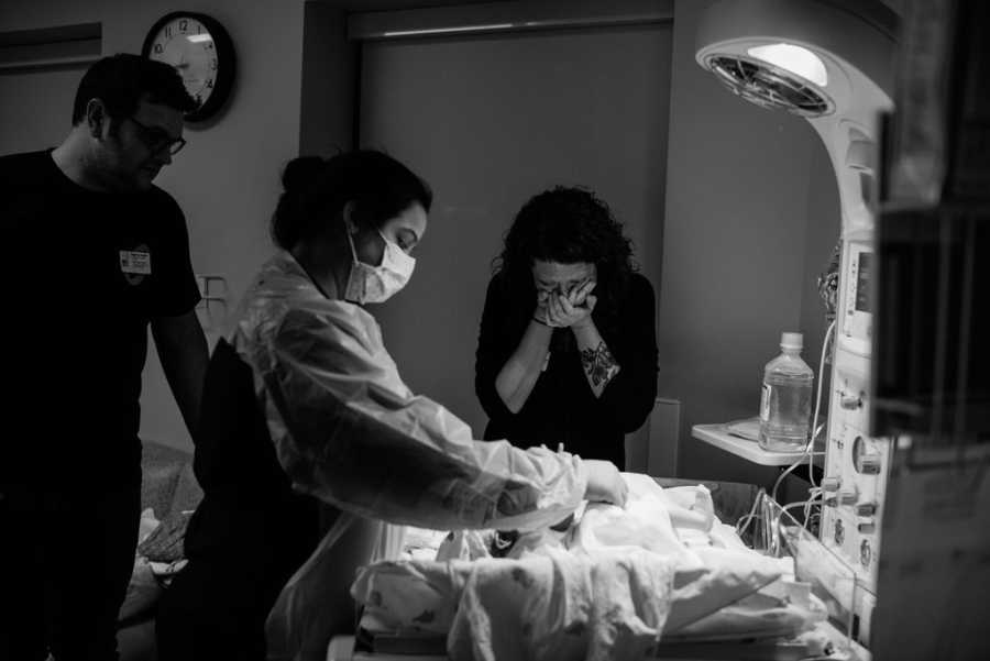 Woman cries as she stands over adopted newborn nurse is tending to