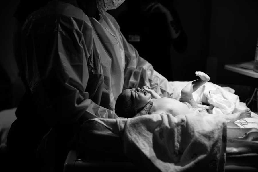 Newborn baby who is being adopted lays on back as nurse tends to her