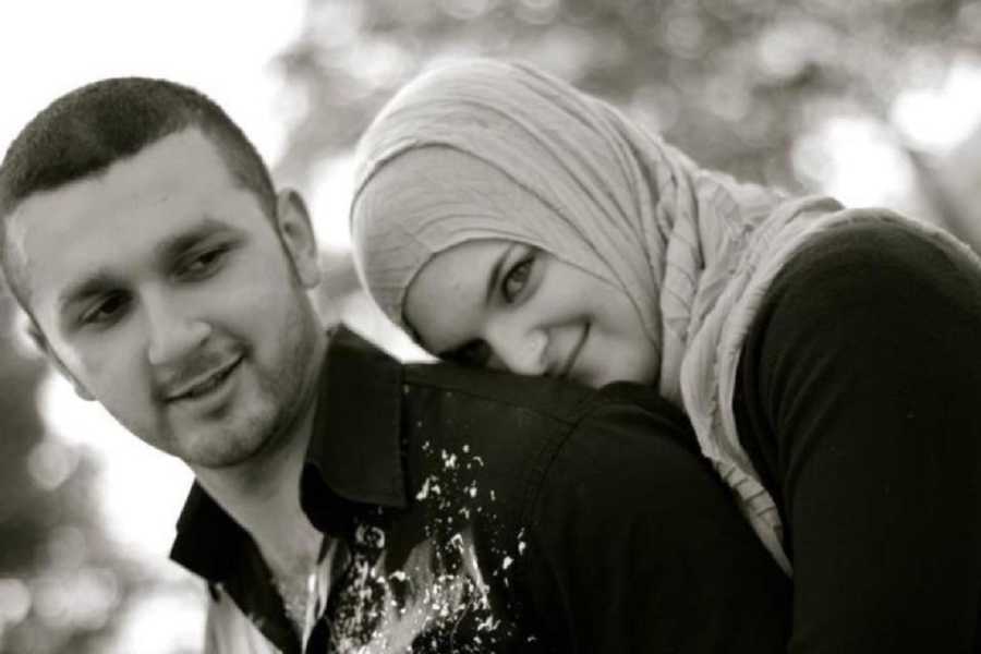 Woman who converted to Islam smiles as she stands behind boyfriend resting head on his shoulder