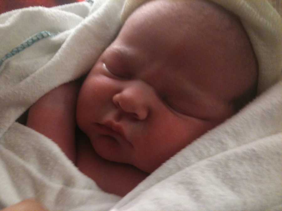 Newborn lays asleep swaddled in white blanket