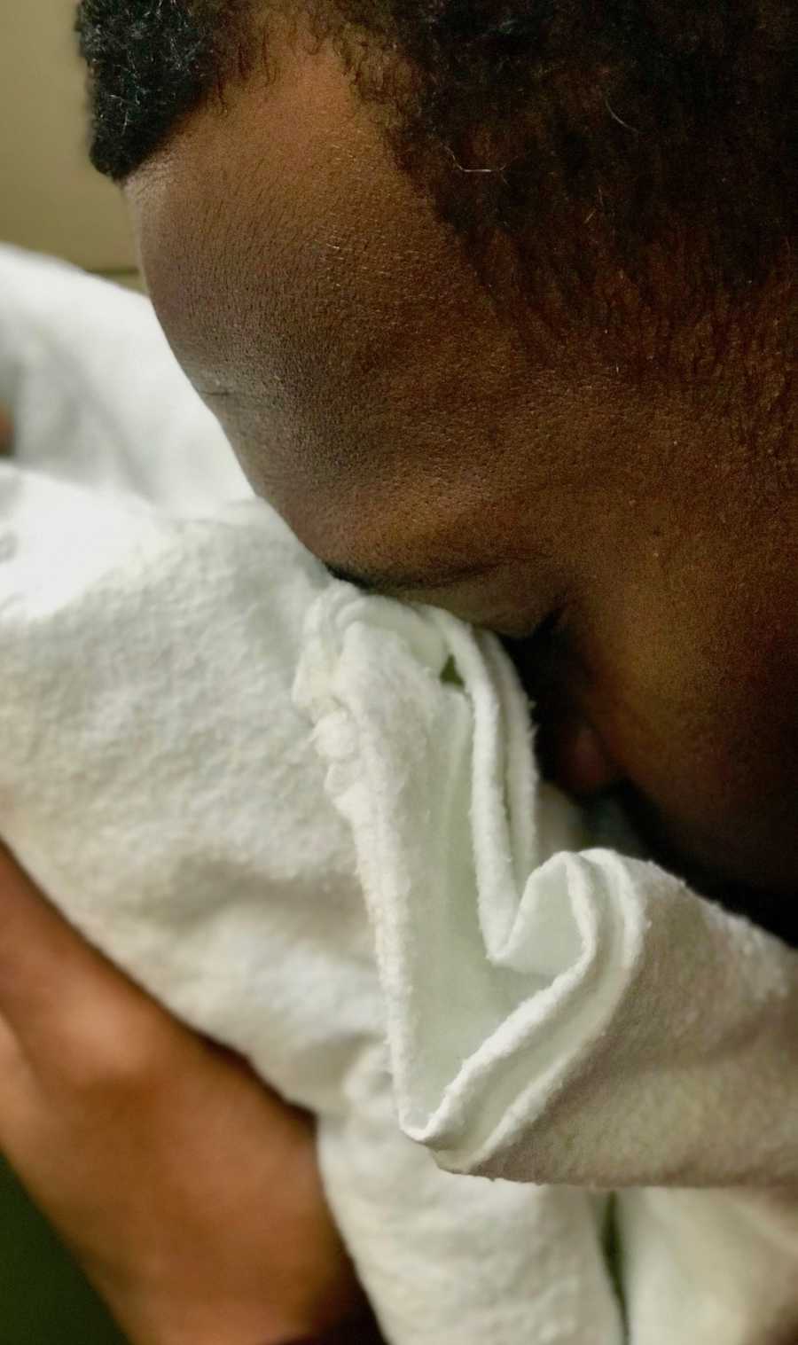 Father smiles into white blanker as his newborn that died the evening of her birth