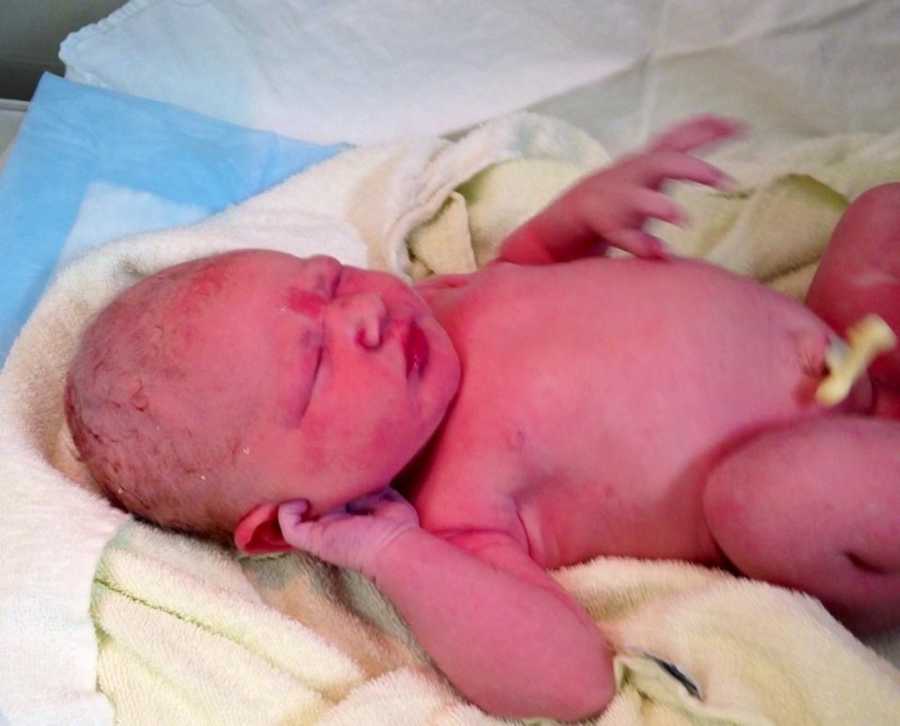 Newborn baby lays on back on yellow towel