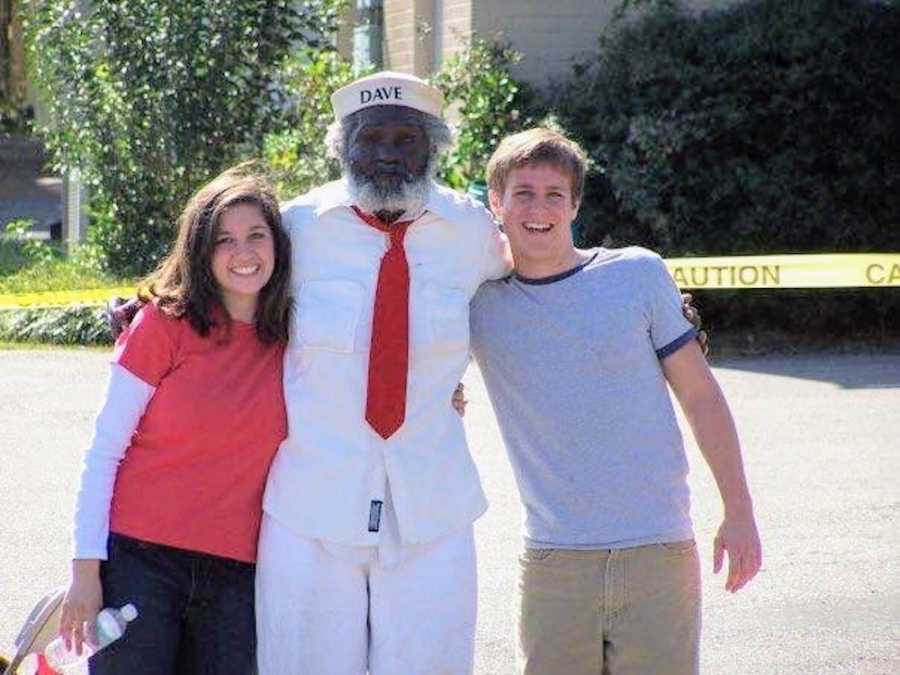 Man and woman stand on either side of this man named Dave who is famous in their town