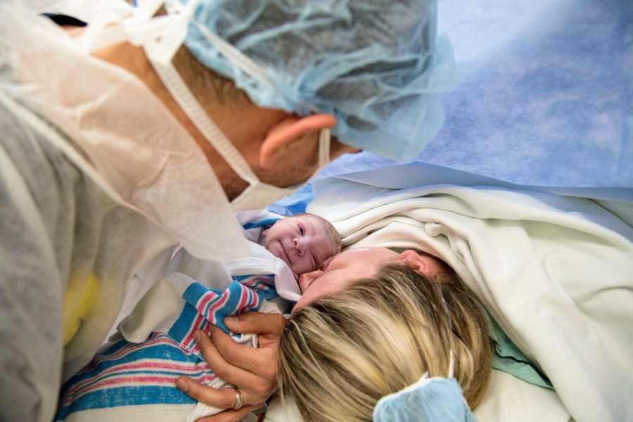 Father holds newborn down to his wife who just had c-section