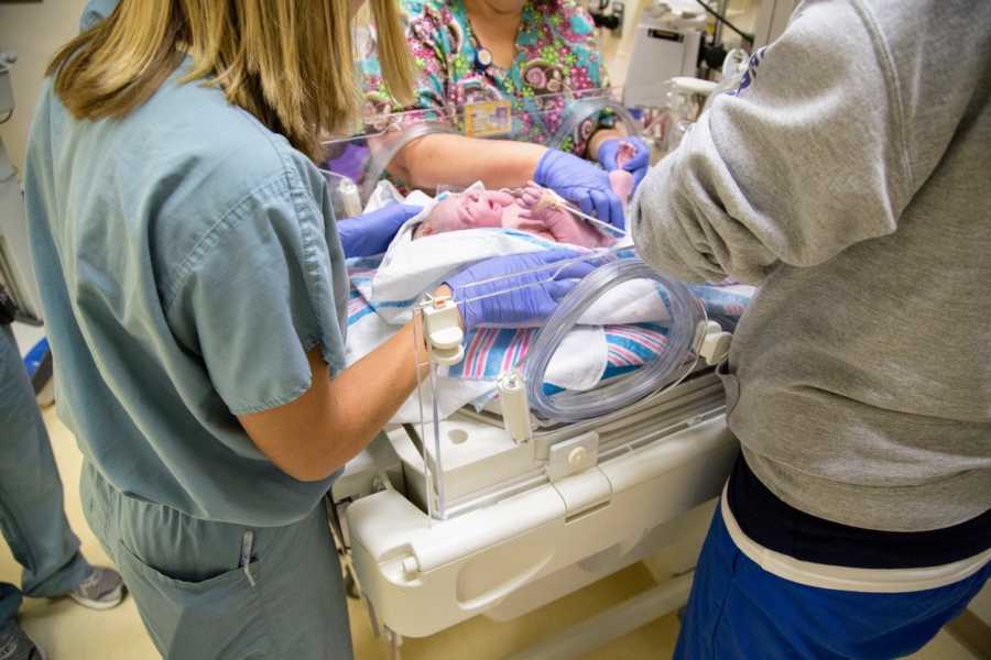 Newborn lays in NICU as nurses tend to him