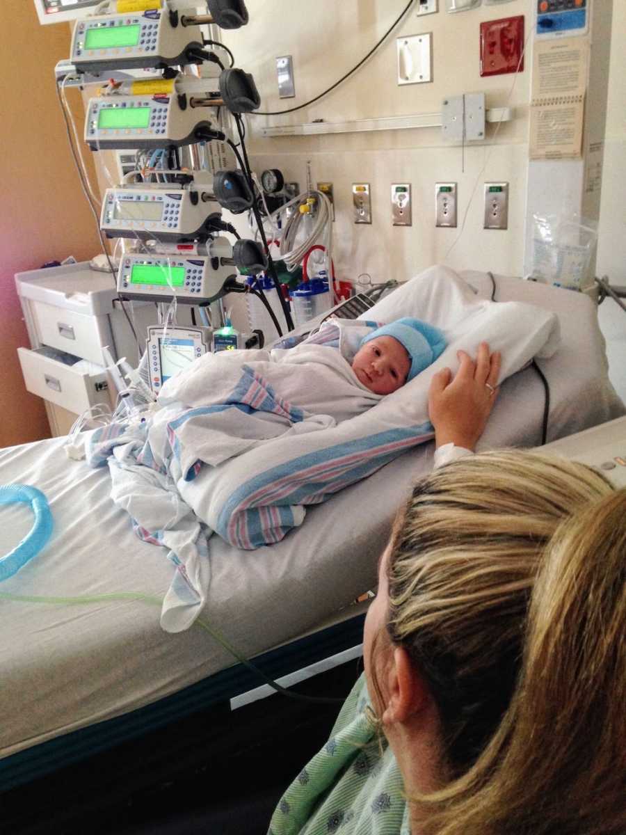 Mother sits beside hospital bed where her newborn lays who has undiagnosed issues