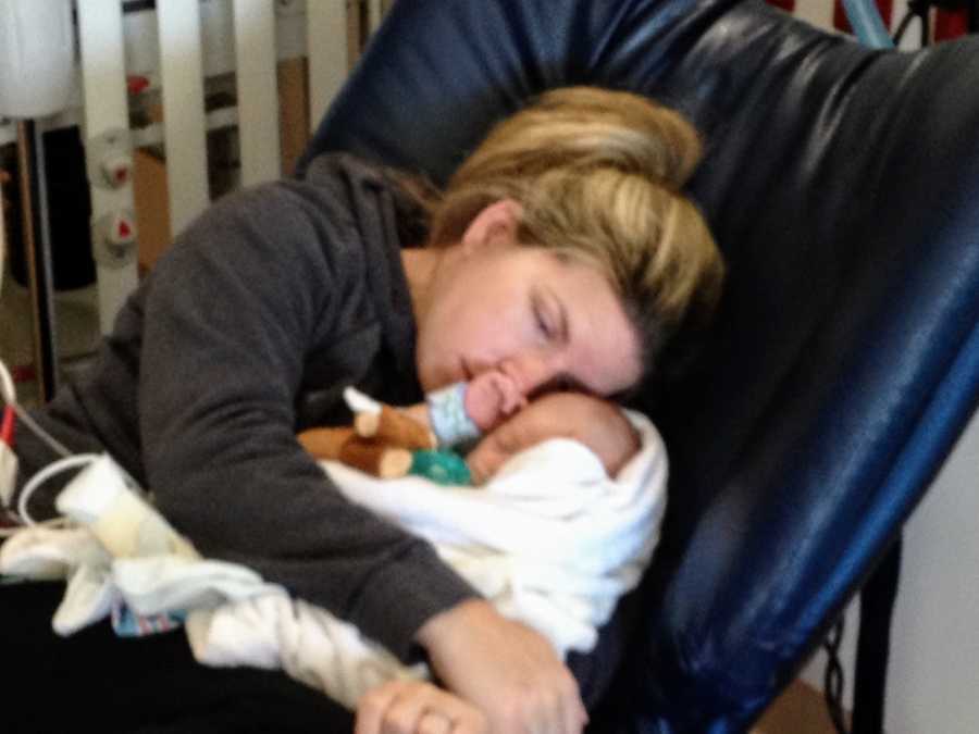 Mother sits in hospital chair holding baby before he has open heart surgery