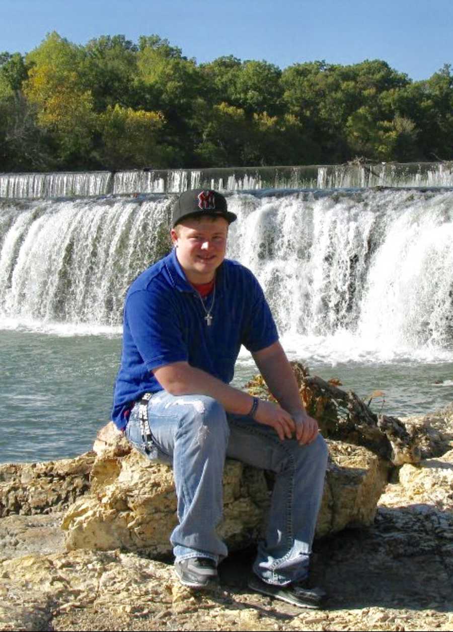 Teen who had seizure from drinking energy drinks sits on rock with waterfall in background