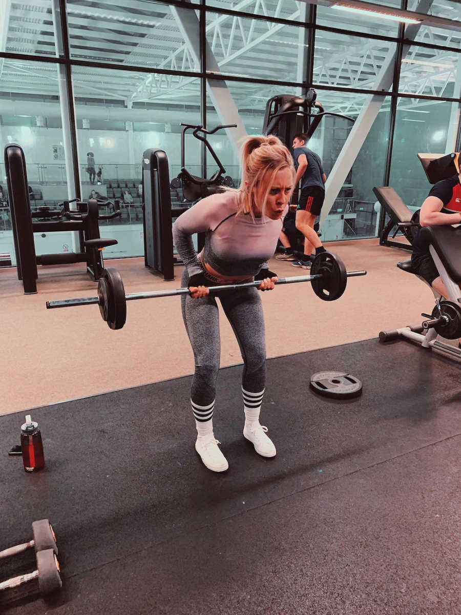 Woman with BPD and CPTSD stands in gym lifting weights