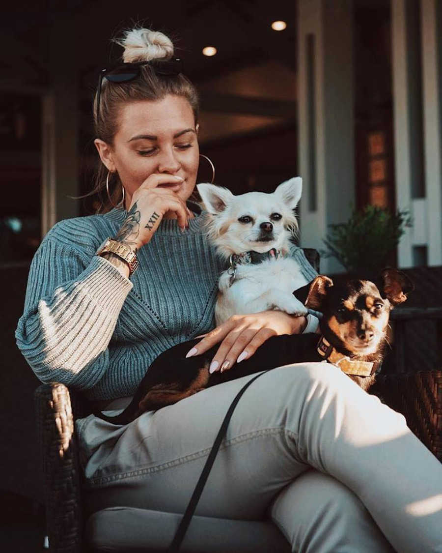 Woman with BPD and CPTSD sits in chair with two little dogs in her lap