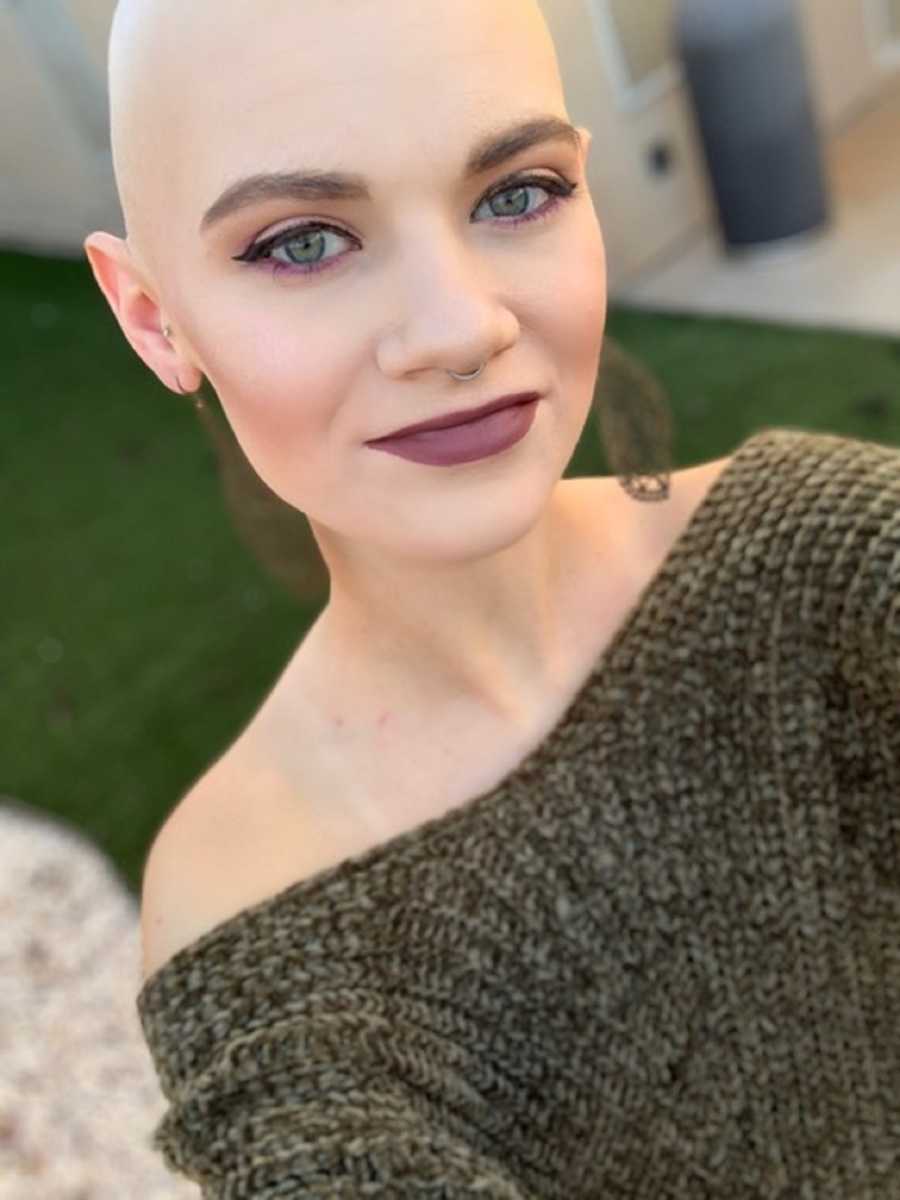 Woman with hodgkin's lymphoma and shaved head smiles in selfie