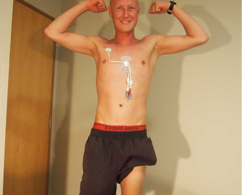New Zealand track runner with Trigeminal neuralgia stands flexing with wires attached to his chest