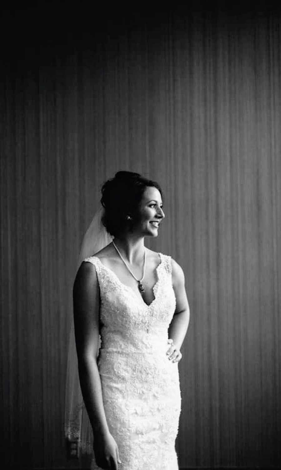 Bride smiles as she looks to her side with hand on hip