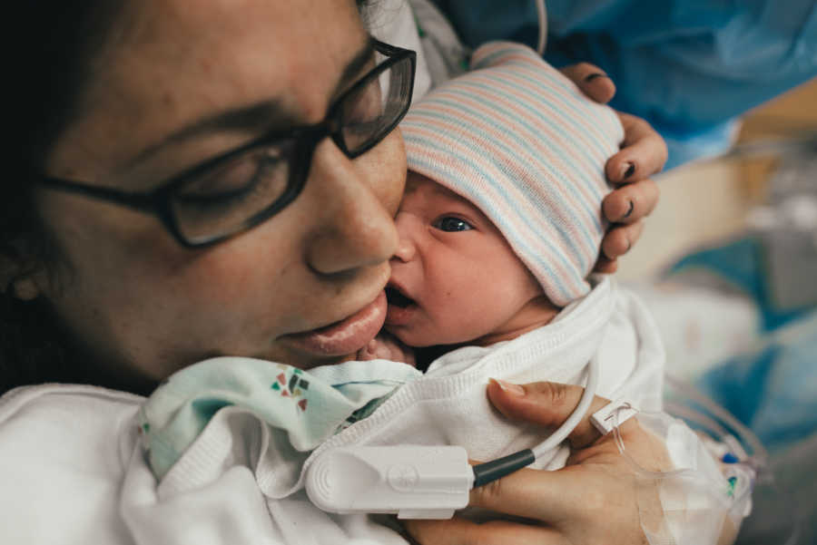 Mother smiles as she holds newborn tight to her chest