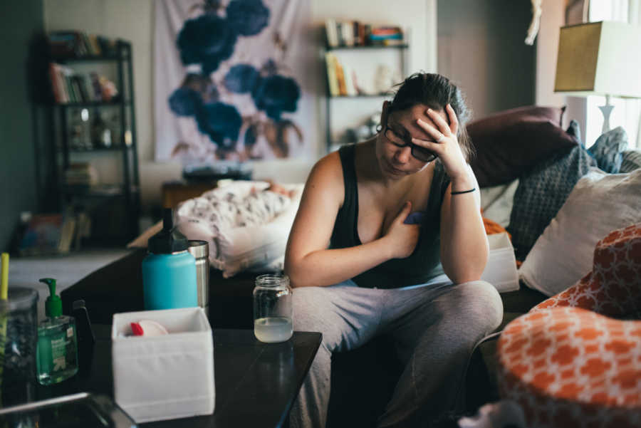 Woman with issues breast feeding sits at home holding her breast