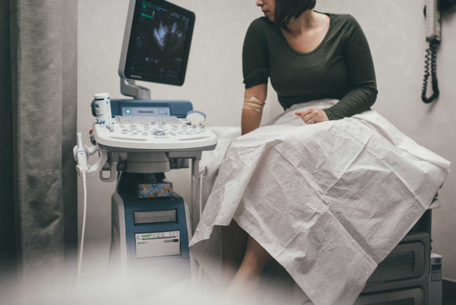 Woman diagnosed with infertility sits in doctor's office looking at ultrasound screen