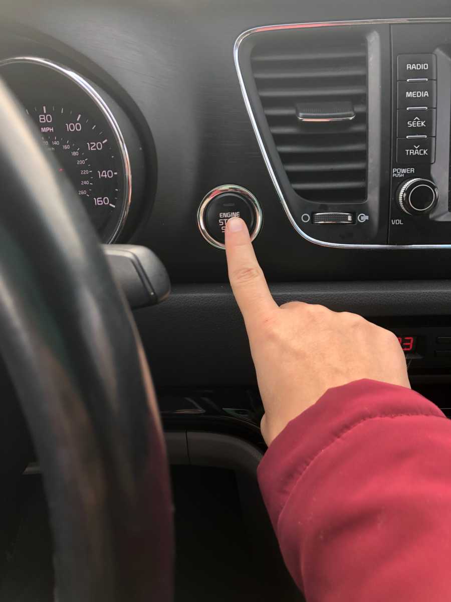 Woman pushing engine start/stop button in car