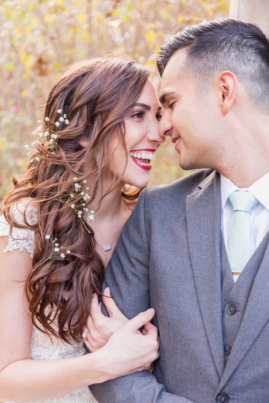 Bride holds onto groom's arm as she smiles looking into his eyes